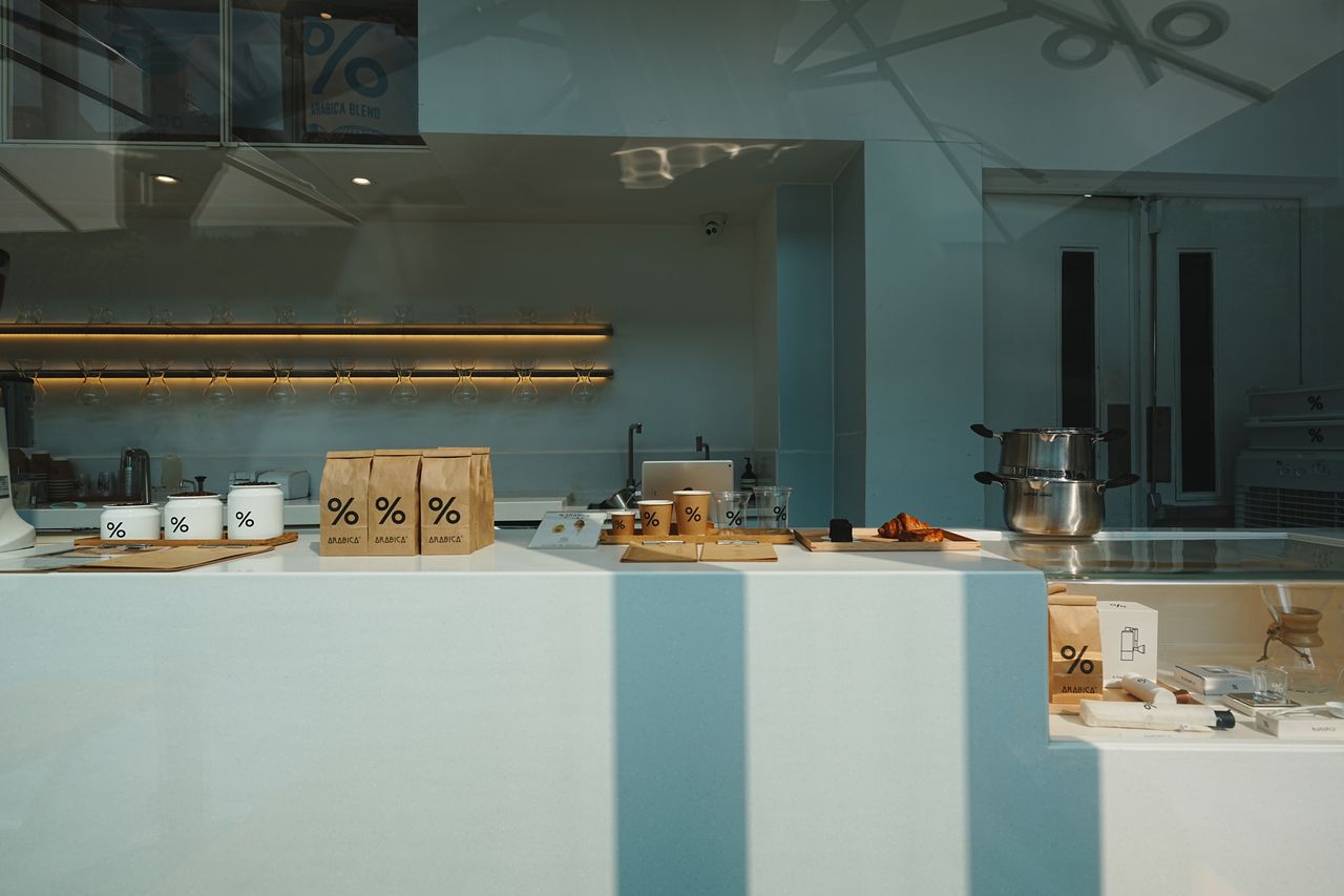 Services Stylish coffee shop interior showcasing retail items and brewing equipment on a minimalist counter.