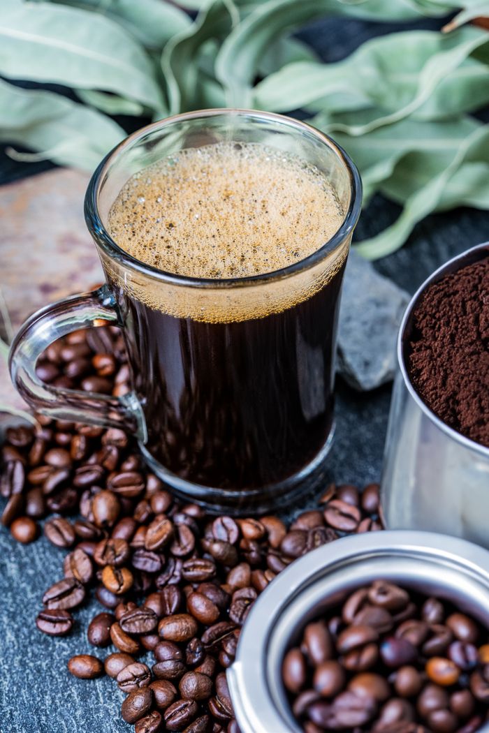 Services A glass of freshly brewed coffee surrounded by coffee beans and ground coffee.