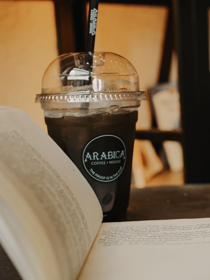 Home Chic café scene with iced coffee and open book, perfect for relaxation or study setting.