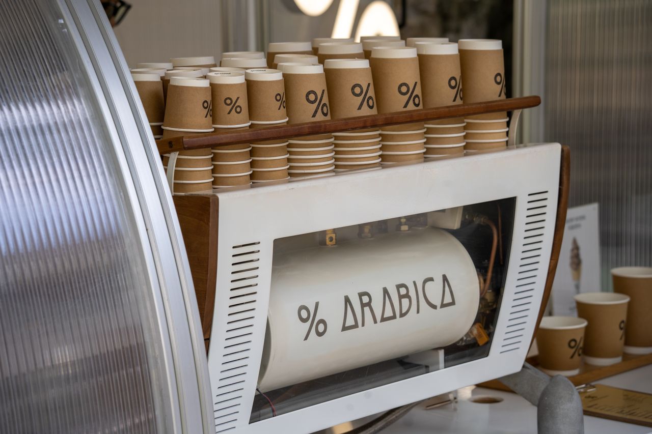 Home Coffee machine with multiple branded paper cups neatly stacked, showcasing coffee culture.